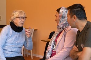 Älterer Frau unterhält sich mit jüngerer Frau und Mann mit Migrationshintergrund