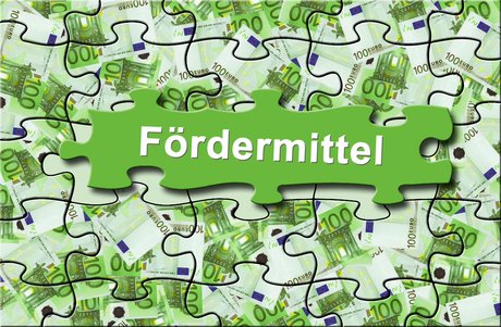 Puzzel-Teile mit 100-Euro-Geldscheinen und dem Aufdruck Fördermittel