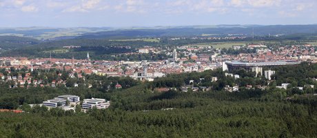 Bild mit einem Stadtpanorama von oben fotografiert. Stadt umgeben von vielen Wäldern