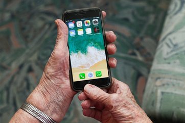 Hände einer alten Frau halten ein Iphone