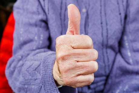 Nahaufnahme einer Hand eines alten Seniors, der mit dem Daumen nach oben zeigt
