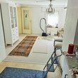 Blick von der Küche ins Wohnzimmer mit Teppichen, Möbeln aber auch Werkzeugen