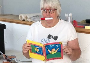 Bild mit einer Frau mit Brille, Buch in der Hand und Stift im Mund