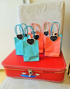 roter Koffer auf dem farbige kleine Tüten (Wundertüten) stehen mit Namensschilchen