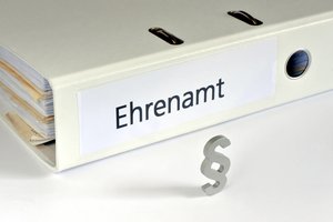 Aktenordner auf dem Ehrenamt steht, davor ein Praragrafensymbol