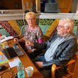 Älterer Mann und ältere Frau sitzen am Laptop vor Theke mit buntem Steinmosaik