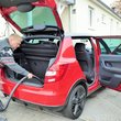 Mann reinigt Kofferraum eines roten Autos