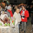 Jung und Alt stehen zusammen im erleuchteten abendlichen Weihnachtsdorf