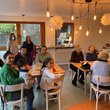 Alte und junge Menschen sitzen gemischt an Tischen in einem Café