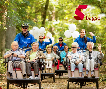 Senioren lachend, werden in Rikschas durch einen Park gefahren