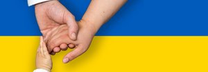 Hand von Mann, Frau und Kind halten sich über ukrainischer blau-gelber Flagge