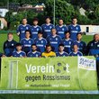 Fußballteam hält Plakat "Vereint gegen Rassismus"