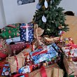 Auf einem Tisch steht ein kleiner Weihnachtsbaum, davor liegen viele weihnachtlich verpackte Geschenke