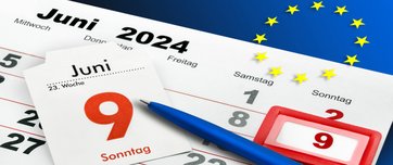 Kalender mit Kugelschreiber der auf den 9. Juni zeigt, Europaflagge im Hintergrund