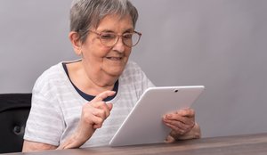 Ältere Dame mit Brille hat Spaß dabei ein Tablet zu bedienen