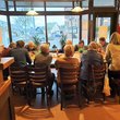 Viele ältere Frauen und Männer sitzen an großem Gruppentisch.