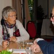 ältere Frau und älterer Mann sitzen gemeinsam an einem Tisch und reden miteinander