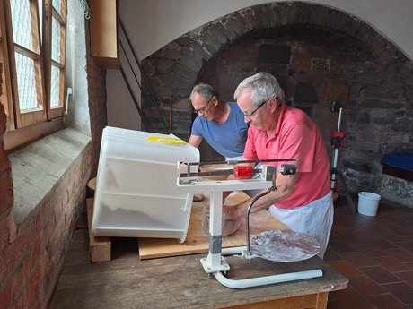 Bild mit zwei Männern, die in einem alten Dorfbackhaus Teige zum Brotbacken vorbereiten
