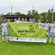 Fußballteam hält Plakat "Vereint gegen Rassismus"