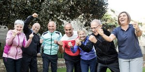 Eine Gruppe von älteren Männern und Frauen in Sportkleidung. Die Personen lachen und ballen die Fäuste