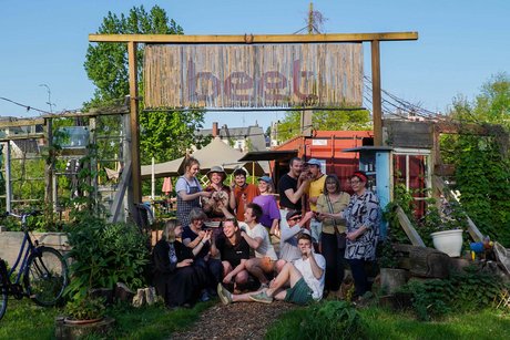 Gruppenfoto mit sitzenden und stehenden Menschen unter einem Holztor, mit der Aufschirft Beet zu einem Gartenbereich.