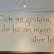 Spruch an der Wand: Erinnere dich an gestern, denke an morgen, aber lebe heute.